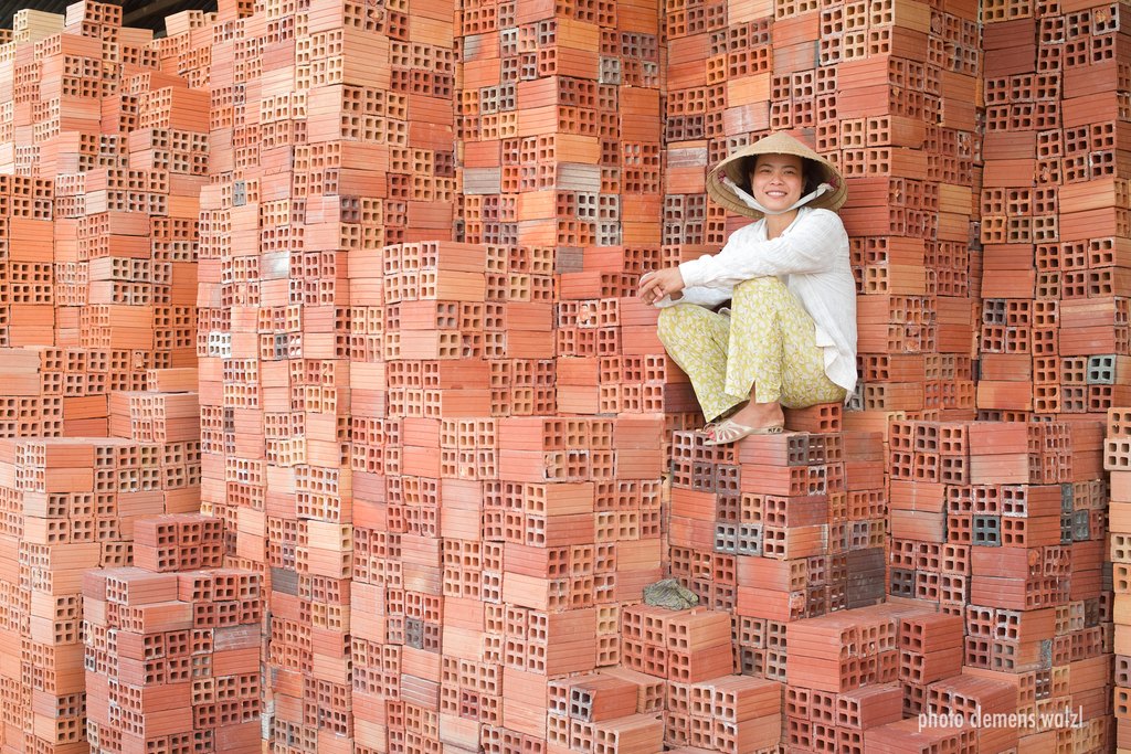 Person sitzt in einer Nische einer Ziegelwand, Vietnam