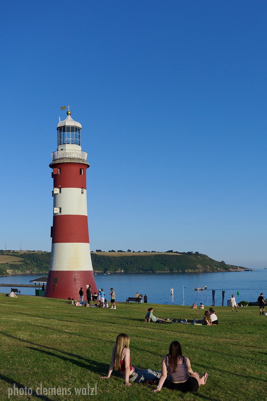 Rot-weiß gestreifter Leuchtturm Smeaton's Tower auf einer Wiese über dem Meer